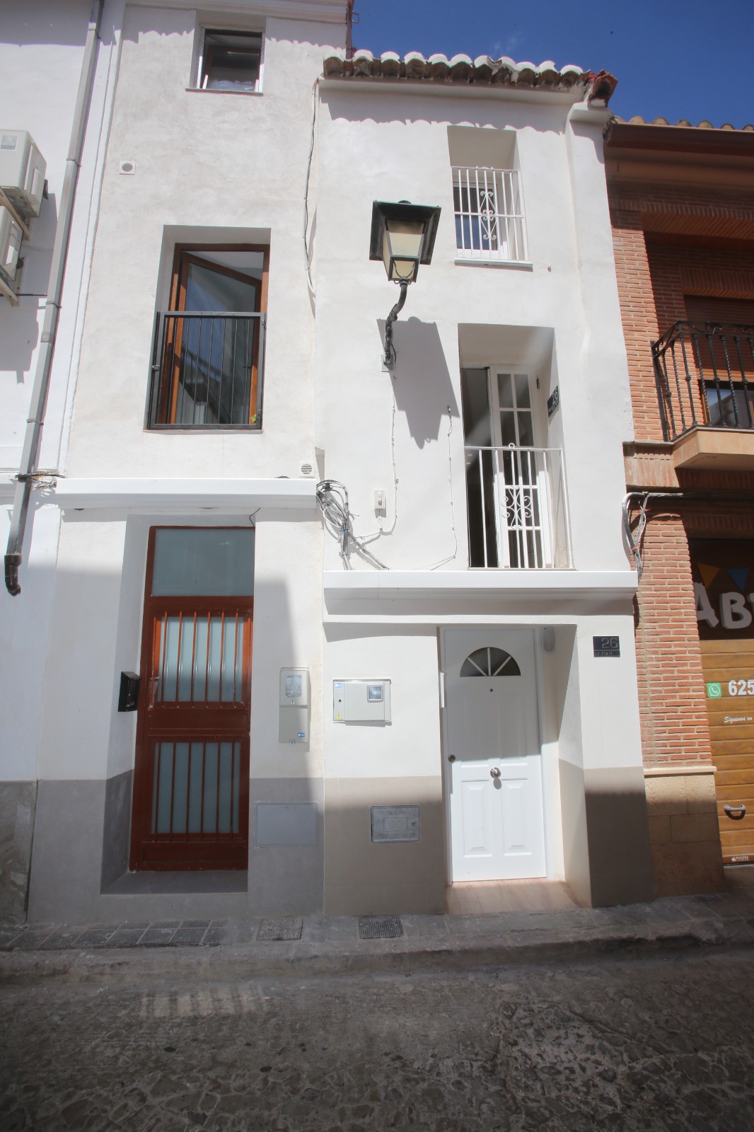 The restored street façade: clean white plaster, a white door numbered 26, Juliet balconies, the lantern kept.